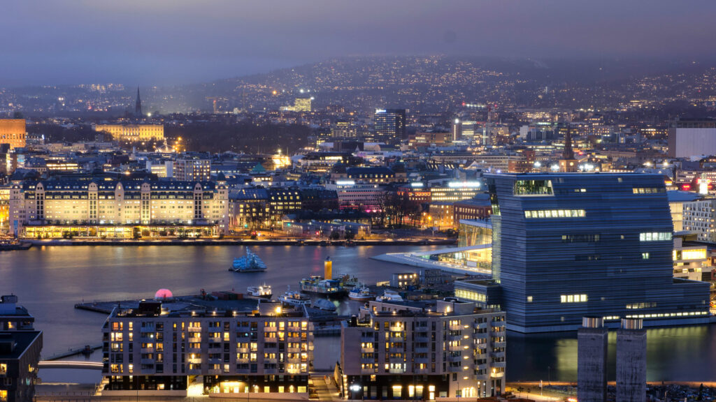 Bildet viser Oslo fra utsynspost på Oslo øst. Sentrum, deler av fjorden og utkant Oslo i vest vises. Det er mørkt, mange bygninger har lys. 