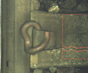 The image shows an automatically detected crack in a concrete sleeper on the railway. The fault is circled in red, the image is otherwise a close-up of the trainline and bolts in brown and grey colours.