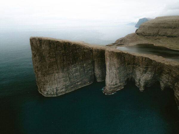 Aerial shot of steep cliffs against a foggy, grey sky and dark seas.