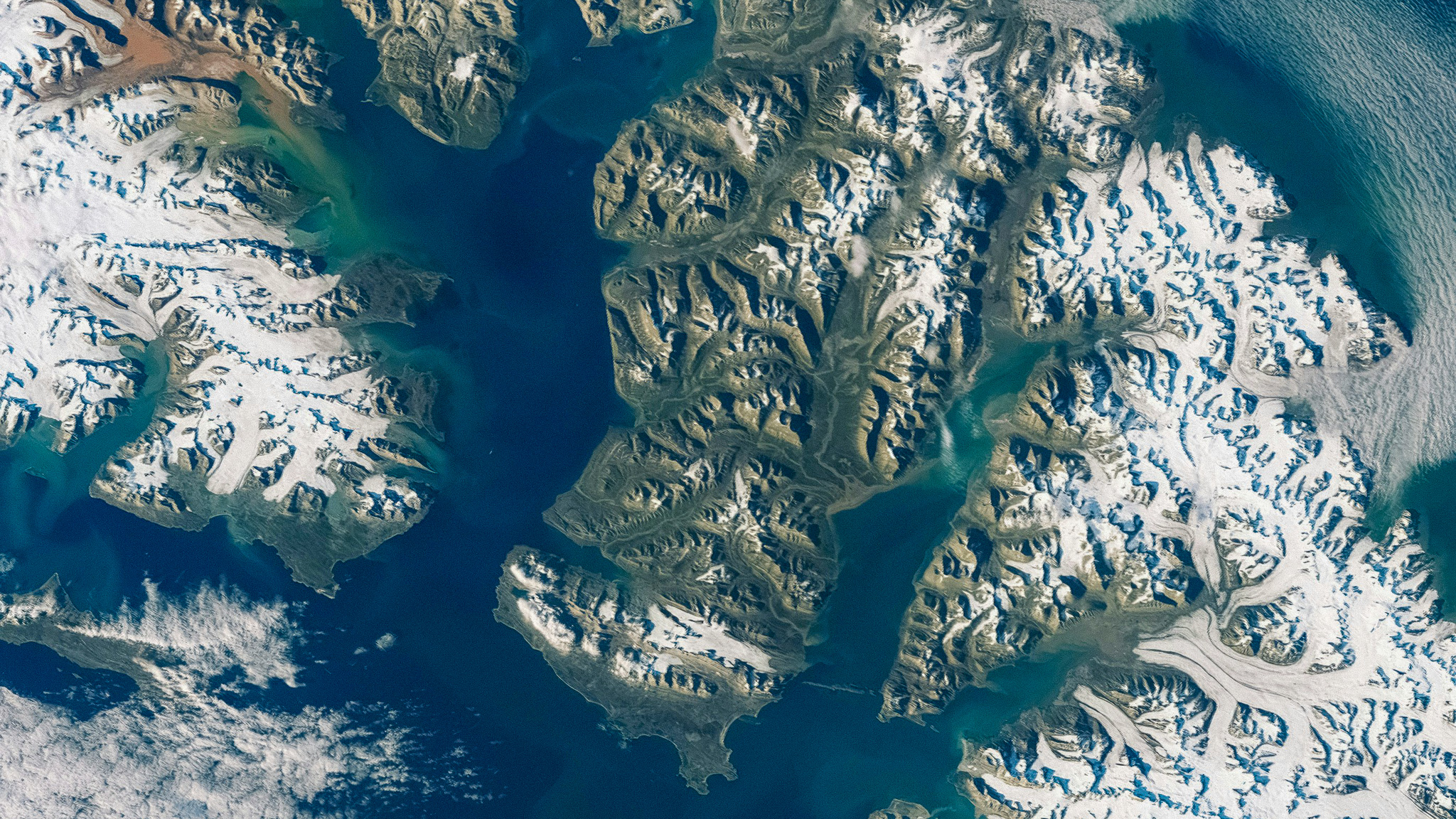 Arctic region seen from satellite. Icy landmass and blue waters.