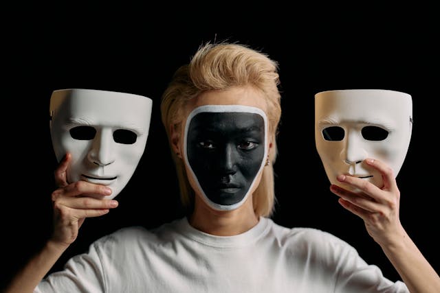 Actor with painted face holding to masks