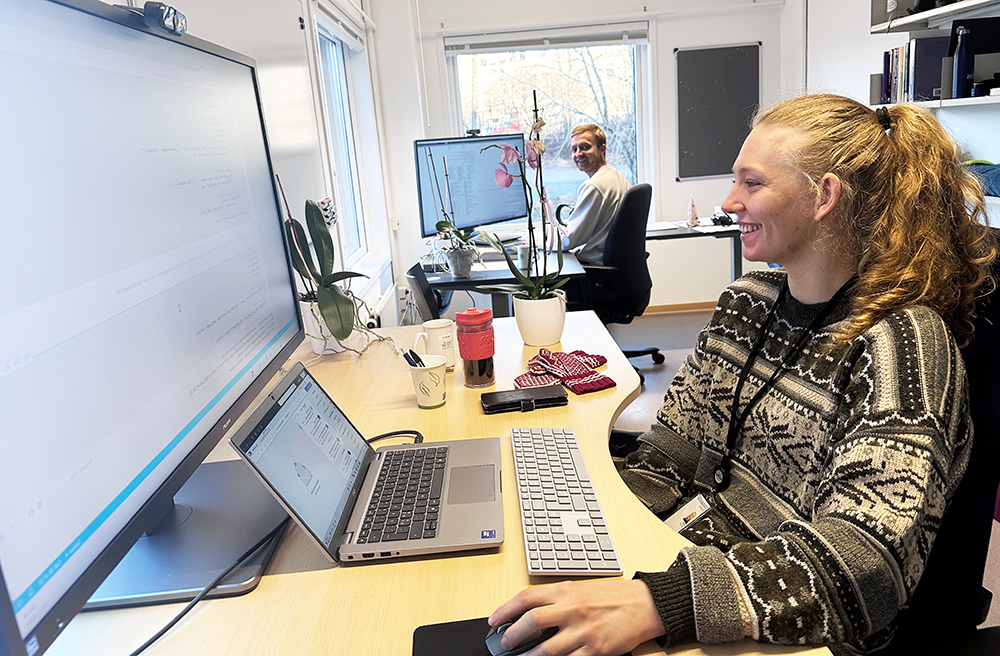 Two young researchers are sat at desks in their office.